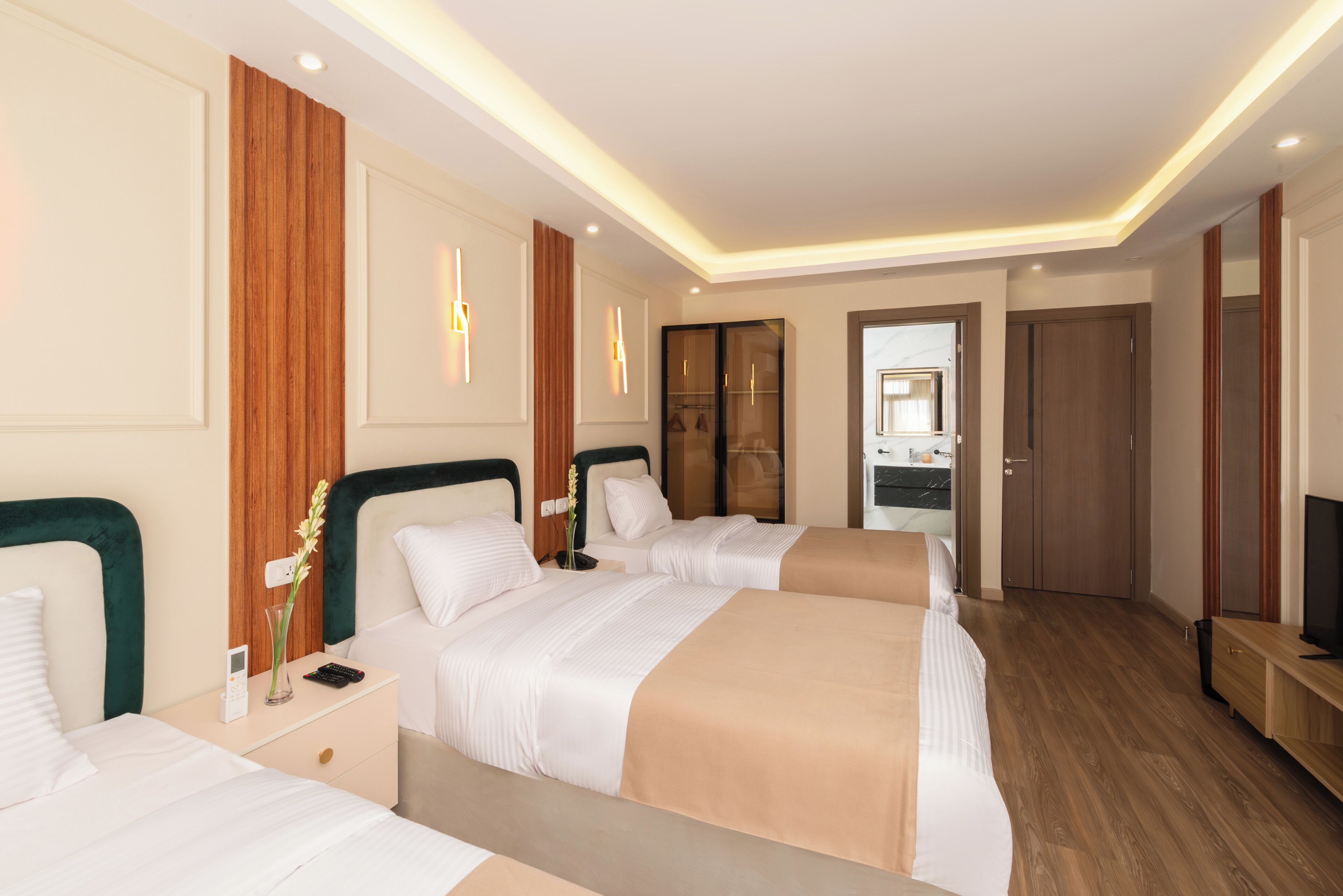 Habitación de hotel con dos camas, televisión y baño visible a través de una puerta abierta.