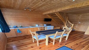 A wooden interior with a dining table and chairs, a kitchen area with a microwave, and a staircase. - Comfortable holiday homes close to the sea (Sarbinowo)