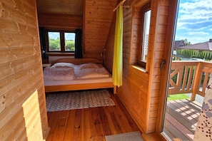 Dormitorio de cabaña de madera con cama, ventana y vistas al exterior.