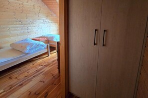 A room with a wooden floor, a bunk bed, and a wardrobe with two doors. - Holiday homes close to the seaside beach (Sarbinowo)