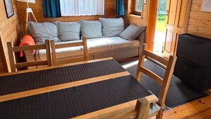 A wooden cabin interior with a sofa, a dining table, and a television. - Holiday homes close to the seaside beach (Sarbinowo)