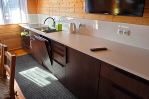 A modern kitchen with a built-in dishwasher, a sink, and a kettle.