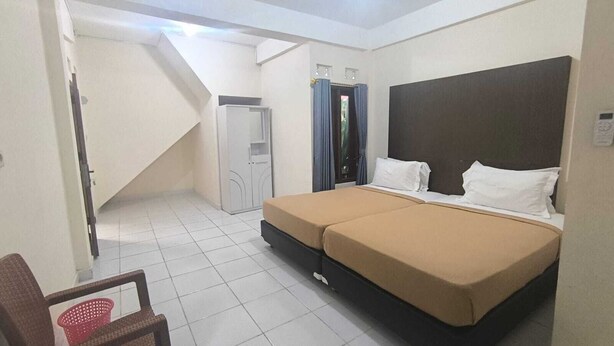 Een slaapkamer met een bed, een stoel, een kledingkast en een trap.