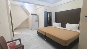 A bedroom with a bed, a chair, a wardrobe, and a staircase. - Tasya Homestay Labuan Bajo (Labuan Bajo)