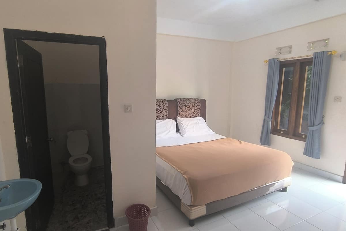 Una stanza con un letto, un bagno con il water e un lavandino.