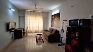 Ein Wohnzimmer mit einer Couch, einem Couchtisch, einem Fernseher und einem Kühlschrank.