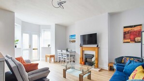 Un salon moderne avec une table basse en verre, un canapé bleu, un canapé gris et une cheminée.