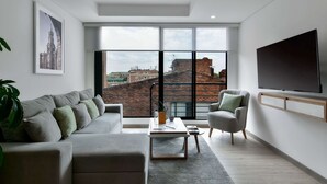Un salon moderne avec une grande fenêtre, un canapé, une table basse et un téléviseur fixé au mur.