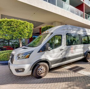 A white van parked in front of a building with a red and white facade.