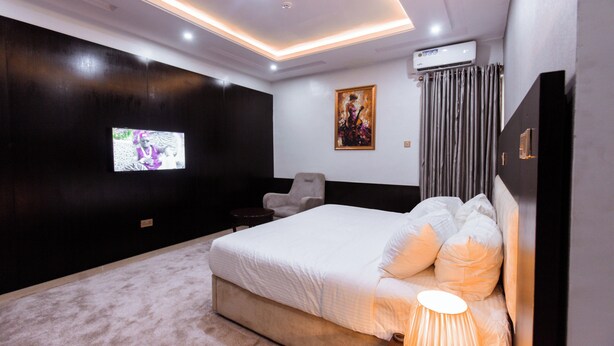 Una camera da letto moderna con un letto grande, una TV a muro e un lampadario.