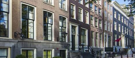 A row of brick buildings with large windows and a red flag.