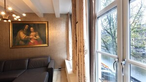 A room with a large window, a painting on the wall, and a sofa. - In the Heart of Old Amsterdam with Canal view (Amsterdam)