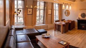 A cozy living room with a sectional sofa, a wooden coffee table, and a dining area with a fireplace. - In the Heart of Old Amsterdam with Canal view (Amsterdam)