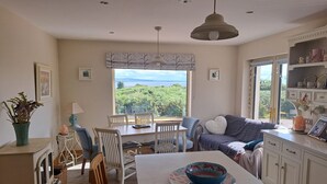 A cozy living room with a dining area, a sofa, and a view of the outdoors.