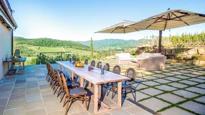 A patio with a dining table and chairs, a large umbrella, and a view of the countryside. - Villa Blu - Seven Bedroom Villa, Sleeps 14 (Greve in Chianti)