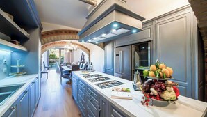 A modern kitchen with a central island, built-in appliances, and a dining area with a view. - Villa Blu - Seven Bedroom Villa, Sleeps 14 (Greve in Chianti)