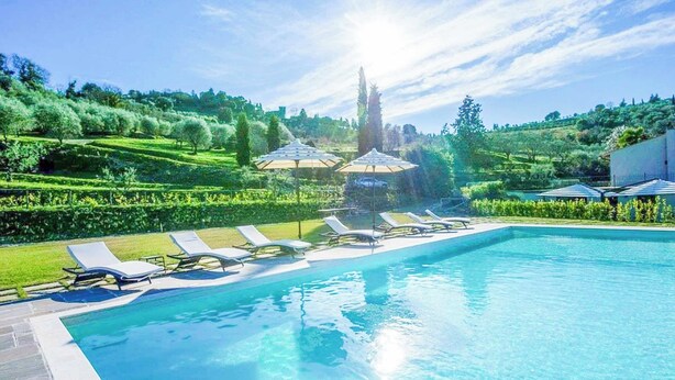 A swimming pool with lounge chairs and umbrellas, surrounded by well-manicured lawns and trees. - Villa Blu - Seven Bedroom Villa, Sleeps 14 (Greve in Chianti)