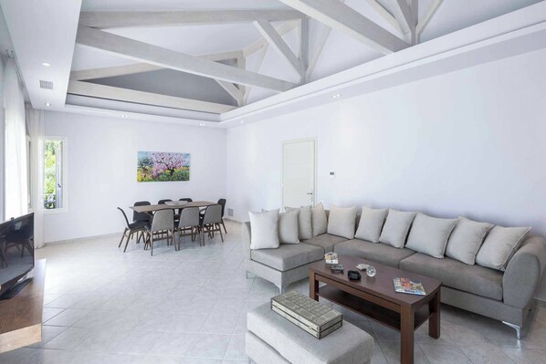 A modern living room with a grey sectional sofa, a wooden coffee table, and a dining area with a table and chairs.