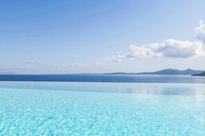 A clear blue pool with a view of the sea and distant mountains.