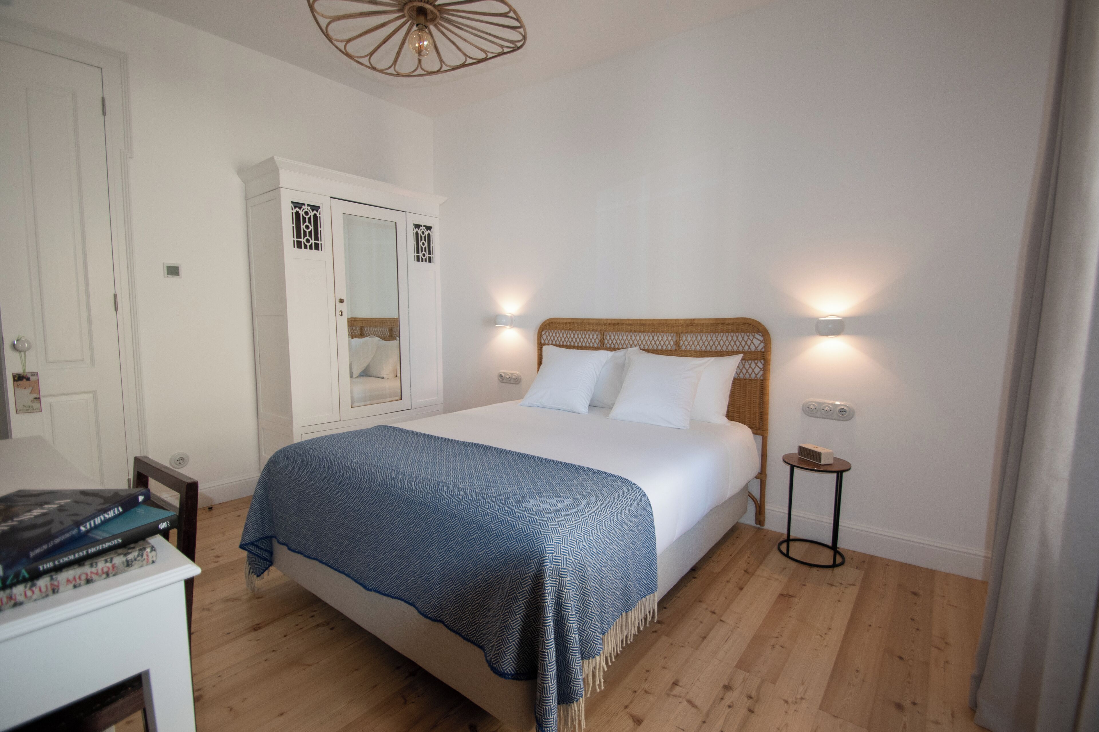A bedroom with a bed, bedside lamps, a wardrobe, and a small table.