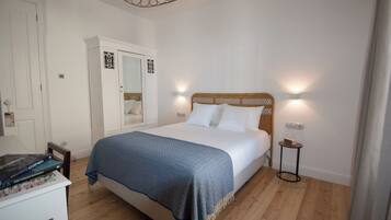 A bedroom with a bed, bedside lamps, a wardrobe, and a small table.