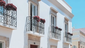 A white building with a red door, multiple windows, and balconies with wrought iron railings. - Casa Amor Olhão (Olhao)