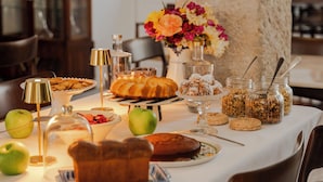 A dining table set with various food items, a vase of flowers, and a lamp. - Casa Amor Olhão (Olhao)