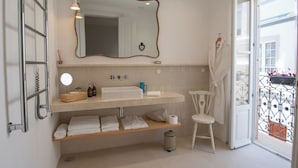 A bathroom with a large mirror, a sink, a towel rack, and a chair. - Casa Amor Olhão (Olhao)