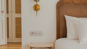 A bedroom with a bed, a bedside table, a wall-mounted light fixture, and a door leading to another room. - Casa Amor Olhão (Olhao)