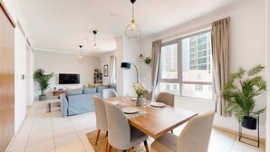 A modern living room with a dining area, a sofa set, and a TV. - Amazing 1 Bed l Burj Khalifa Views l King Size Bed (Downtown Dubai)