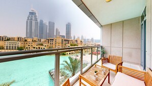 A balcony with a view of a cityscape and a turquoise body of water. - Amazing 1 Bed l Burj Khalifa Views l King Size Bed (Downtown Dubai)