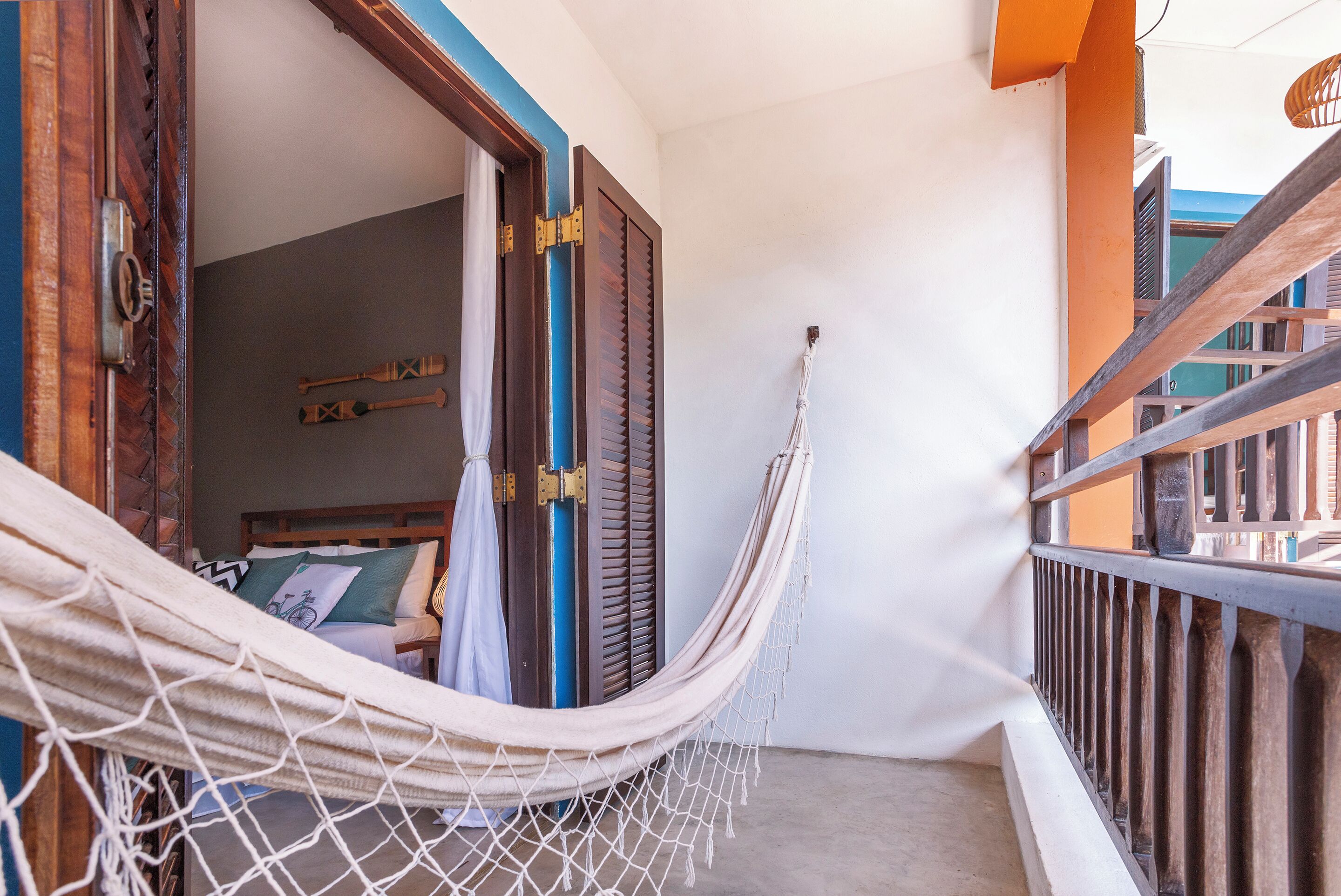 Una hamaca en un balcón con vistas a una habitación con cama y ventana.