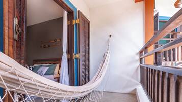 Una hamaca en un balcón con vistas a una habitación con cama y ventana.