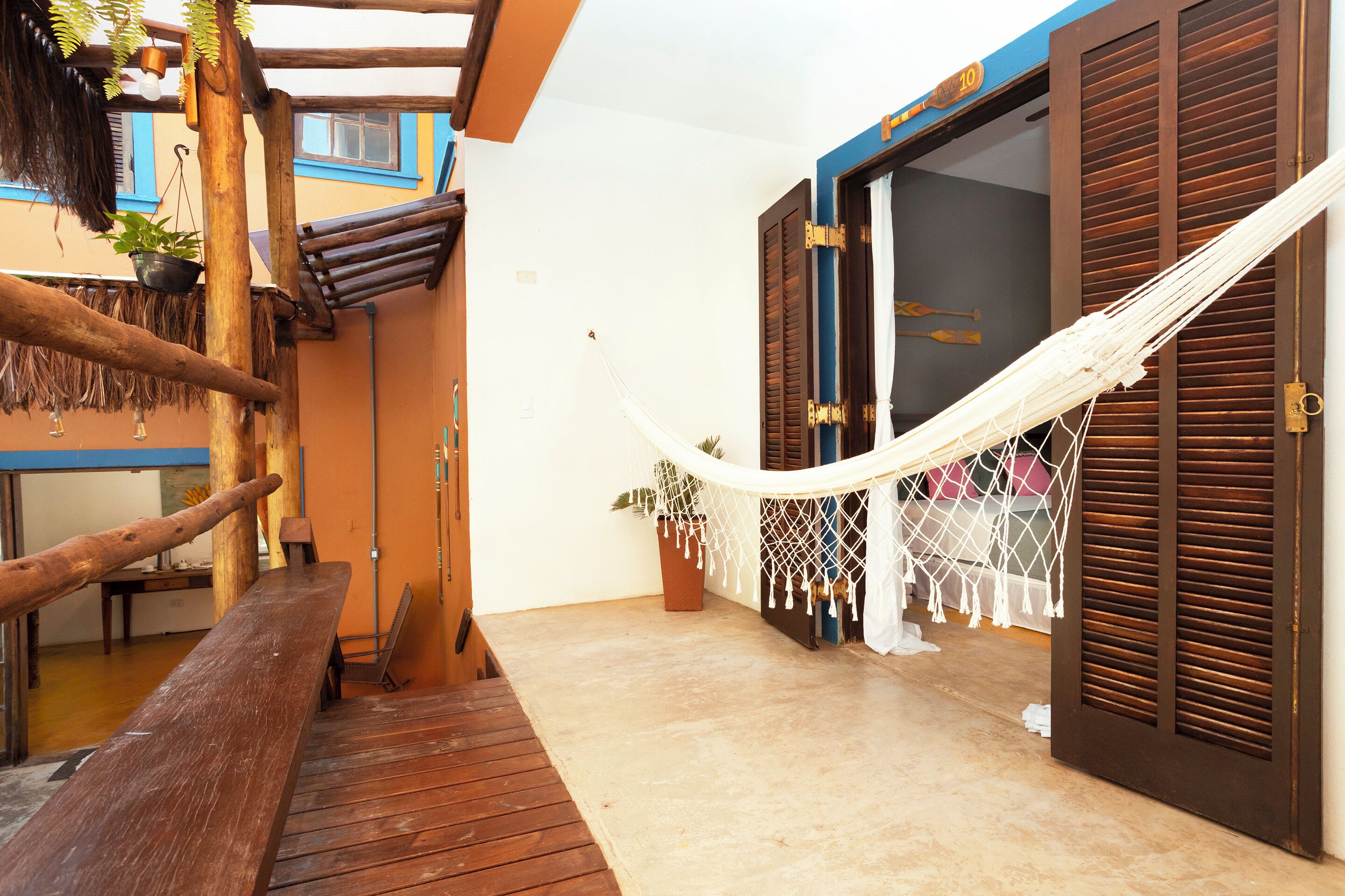 A wooden deck with a hammock, a bench, and a potted plant.