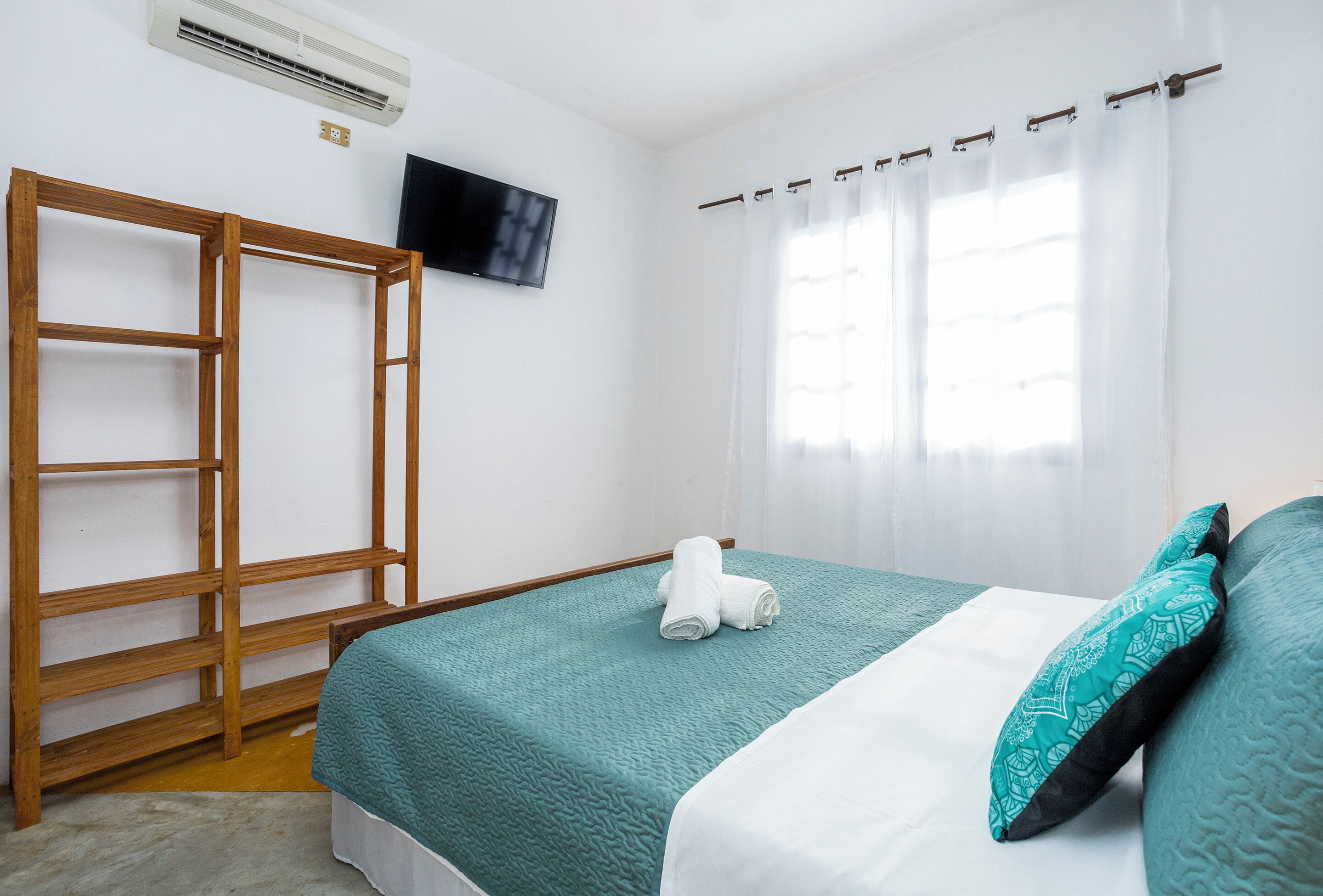 Quarto com cama, escada de madeira, televisão de tela plana e janela com cortinas.