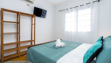 Quarto com cama, escada de madeira, televisão de tela plana e janela com cortinas.