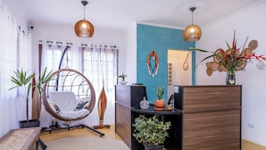 A room with a hanging chair, a desk, a potted plant, and a wooden cabinet. - Pousada Aysu Maresias (São Sebastião)