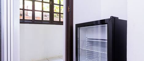 A room with a refrigerator, a window, and a tiled floor.