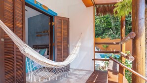 A hammock on a wooden deck with a view of a pool and lush greenery. - Pousada Aysu Maresias (São Sebastião)