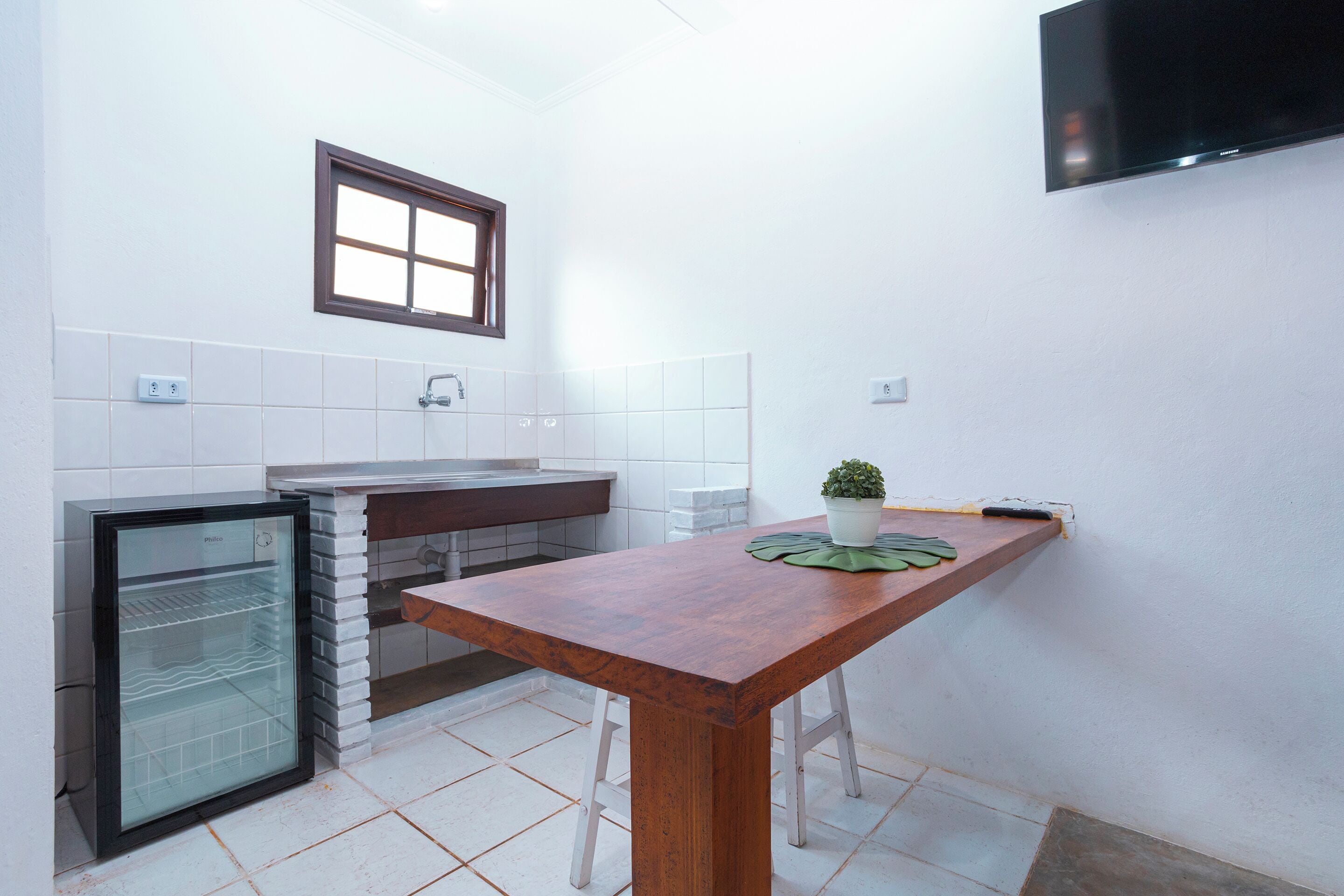 Una cocina compacta con refrigerador, pileta y una mesa de madera.