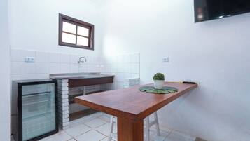 Una cocina compacta con refrigerador, pileta y una mesa de madera.
