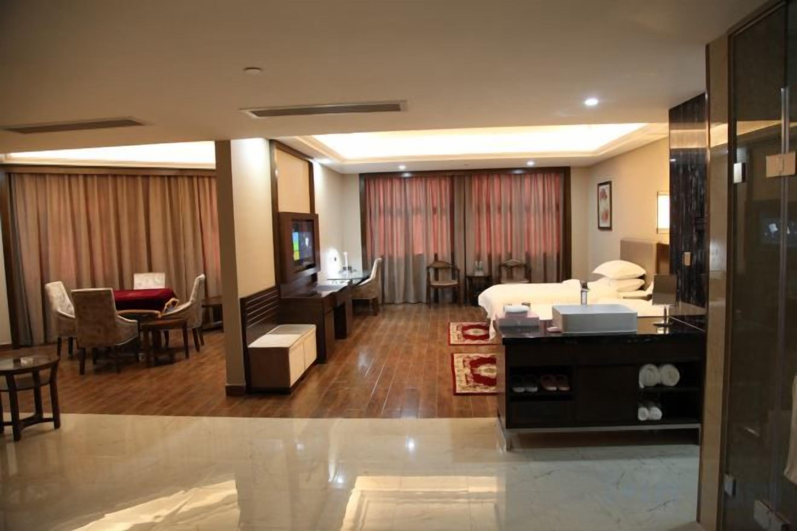 A hotel room with a bed, desk, chairs, and a TV.