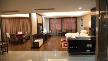 A hotel room with a bed, desk, chairs, and a TV.