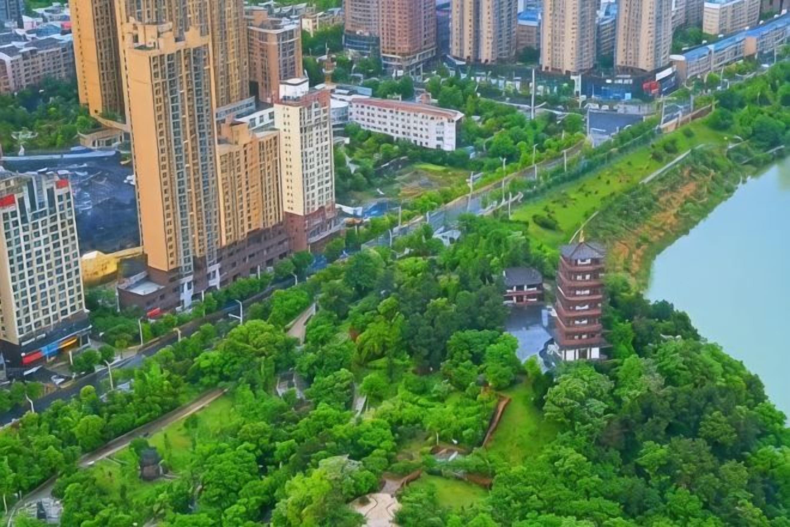 A high-rise building complex with a river and a park with a pagoda.