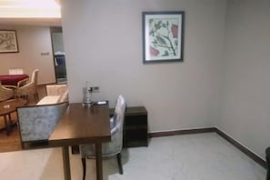 Un área de comedor con una mesa y sillas de madera, un cuadro en la pared y piso alfombrado.