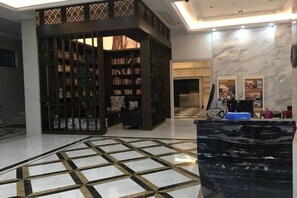 A lobby with a checkered floor, a reception desk, and a bookshelf area. - Jianan Business Hotel (Yongzhou)