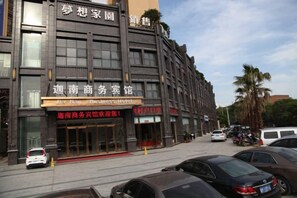 A multi-story hotel with a business hotel sign, a parking lot, and a palm tree in the background. - Jianan Business Hotel (Yongzhou)