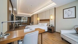 A hotel room with a bed, a desk, a chair, a sofa, and a small table. - Jianan Business Hotel (Yongzhou)