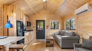 A wooden cabin interior with a kitchen, dining area, and living room. - Happy Travelers RV Resort (Thonotosassa)
