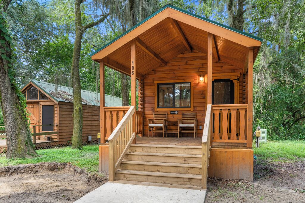 A wooden cabin with a porch, steps, and a window.